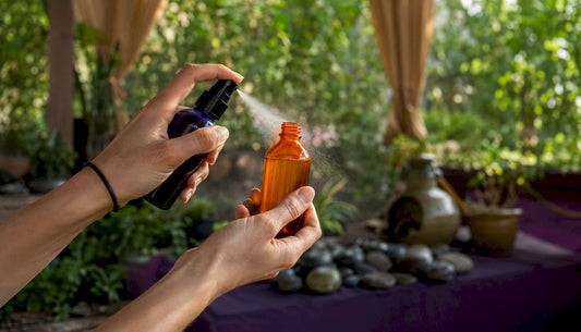 Hands spraying botanical mist on glass bottle