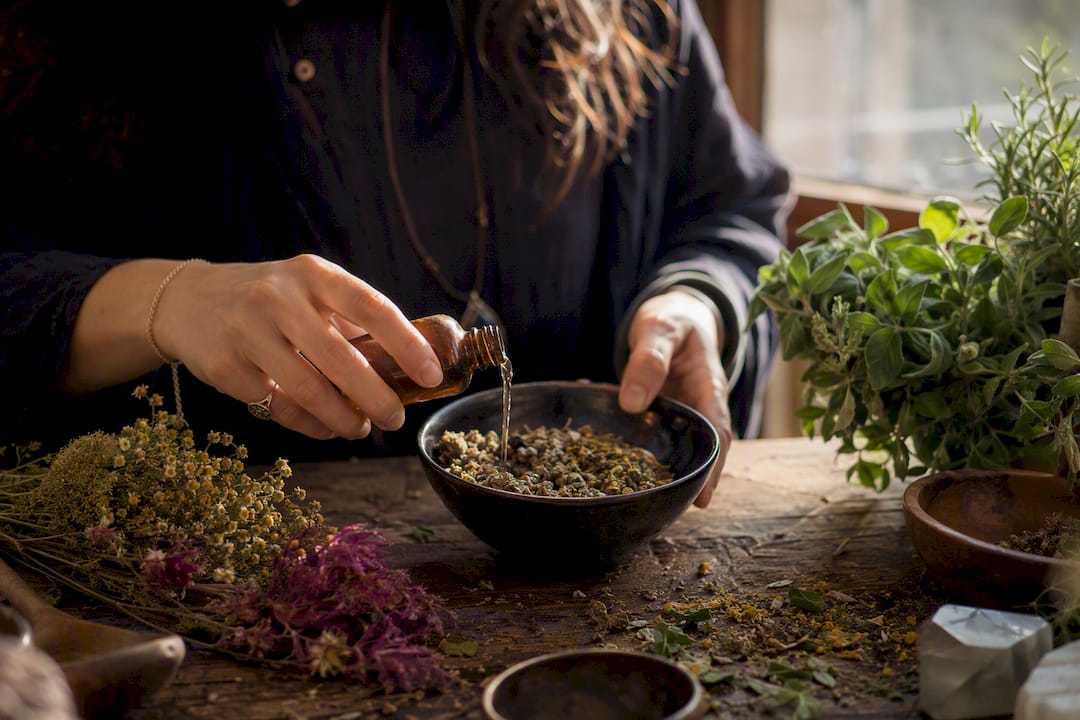 Hands pouring alcohol into herbal tincture jar