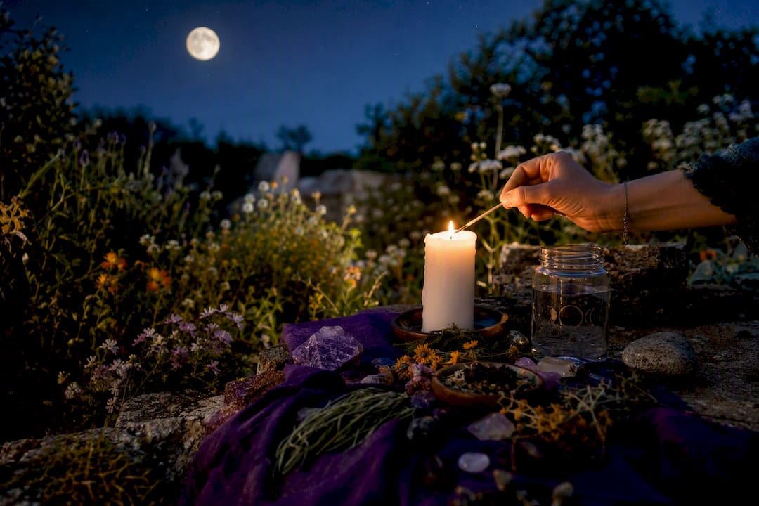 Hand lighting candle on full moon altar
